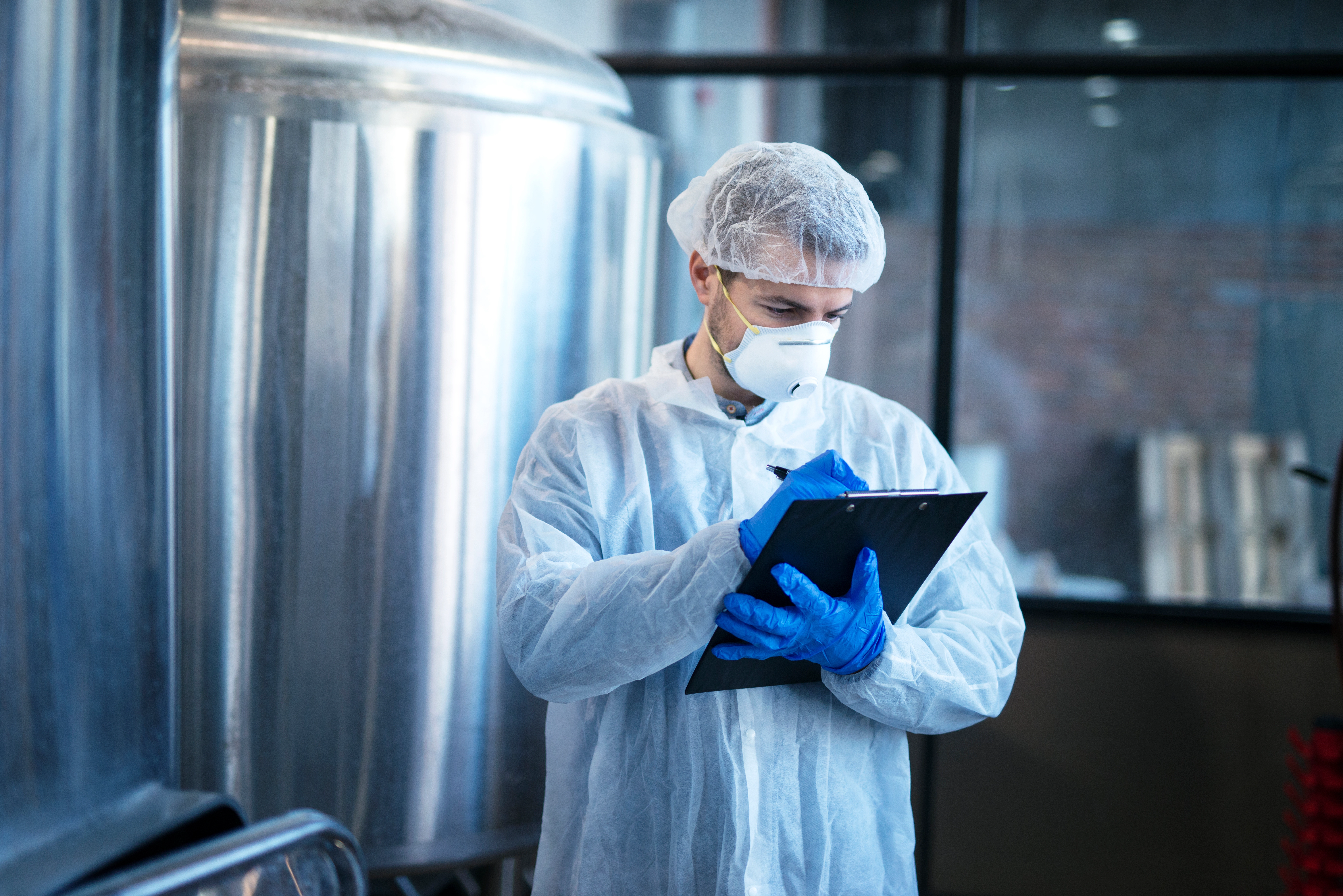 HACCP in Saudi food industry – food safety inspector in protective clothing checking quality standards in a factory for compliance and hygiene.
